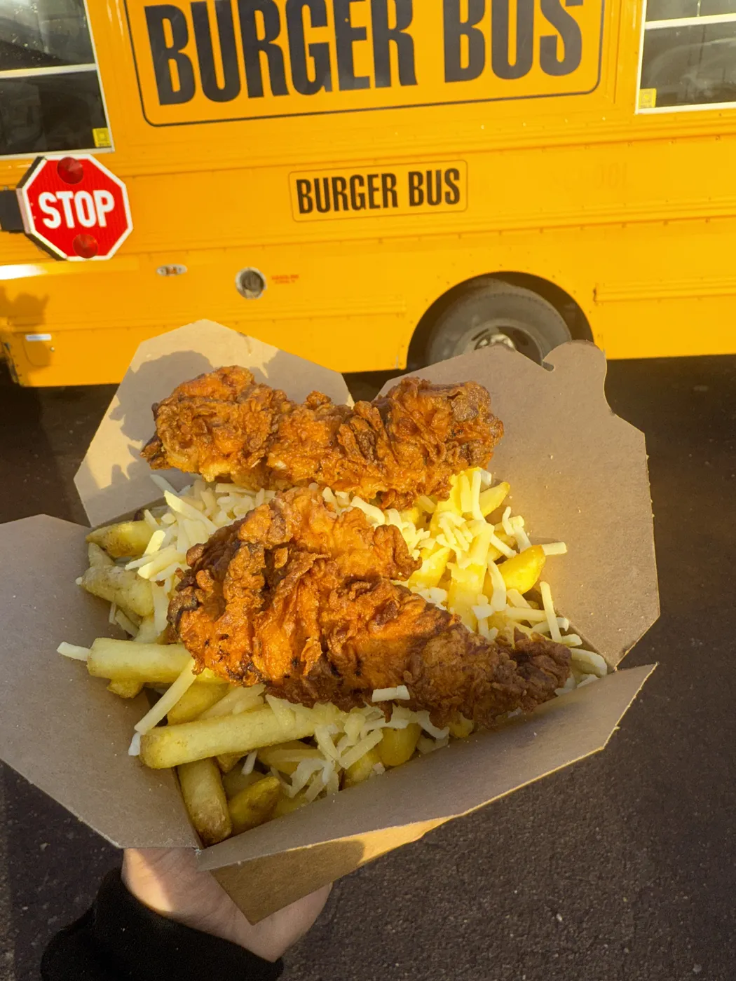 A box of chips and chicken strips held up in front of the Burger Bus