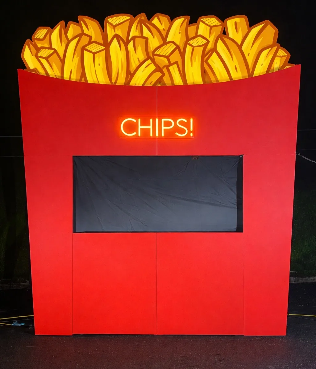 The CHIPS! stall at night, a giant red chip box with a neon CHIPS! sign